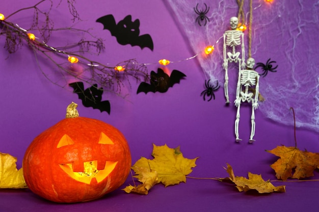 Fondos de Halloween del esqueleto de la telaraña de calabaza Jack Lantern en una cuerda arañas y murciélagos negros sobre un fondo púrpura con un paisaje terrible Horror y unas vacaciones aterradoras con espacio para copiar