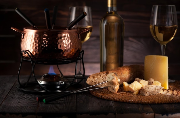 Fondue com queijo e vinho branco em um fundo escuro de madeira