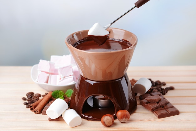 Fondue de chocolate com bombons de marshmallow na mesa de madeira