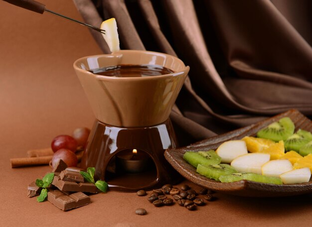 Fondue de chocolate com frutas em fundo marrom