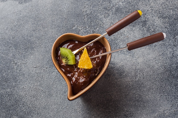 Fondue de chocolate com frutas em um concreto escuro