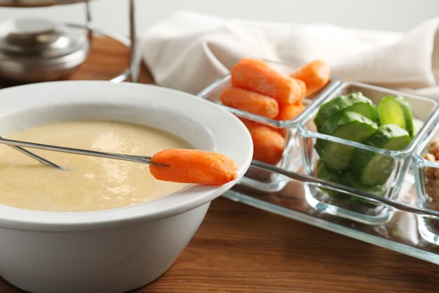 Fondue de queijo com cenoura na mesa