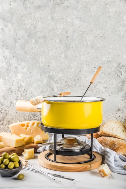 Fondue suíço gourmet em panela de fondue tradicional, com garfos, queijos diversos, azeitonas, pão e uva