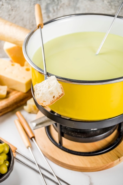 Fondue suíço gourmet em panela de fondue tradicional, com garfos, queijos diversos, azeitonas, pão e uva