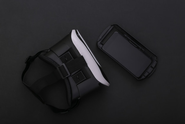 Fone de ouvido de realidade virtual e smartphone em fundo preto. Dispositivos modernos. Vista do topo