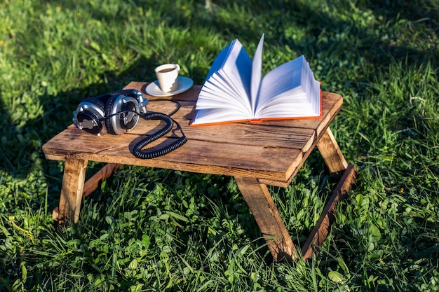 fone de ouvido livro e café em uma madeira na natureza