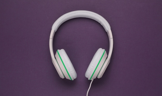 Foto fones de ouvido brancos clássicos com fio em fundo de papel roxo escuro