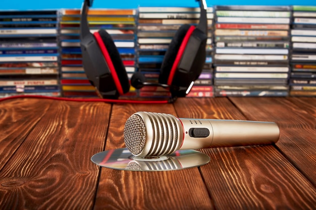 Fones de ouvido com CDs e um microfone de áudio na mesa de madeira