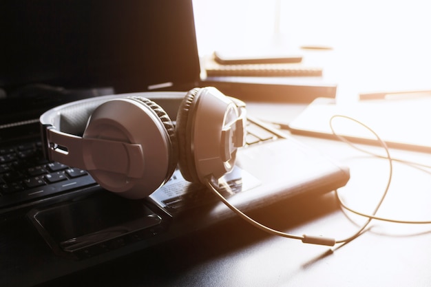 Fones de ouvido, computador tablet e laptop na mesa preta