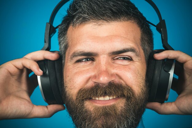 Fones de ouvido. Conceito de música, alegria, felicidade, lazer, tecnologia, estilo, estilo de vida e pessoas - homem barbudo ouvindo música usando fone de ouvido. Homem feliz hipster ouvindo música em fones de ouvido.