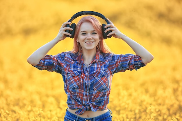 fones de ouvido de áudio verão música menina em um campo de flores, jovem primavera feminina