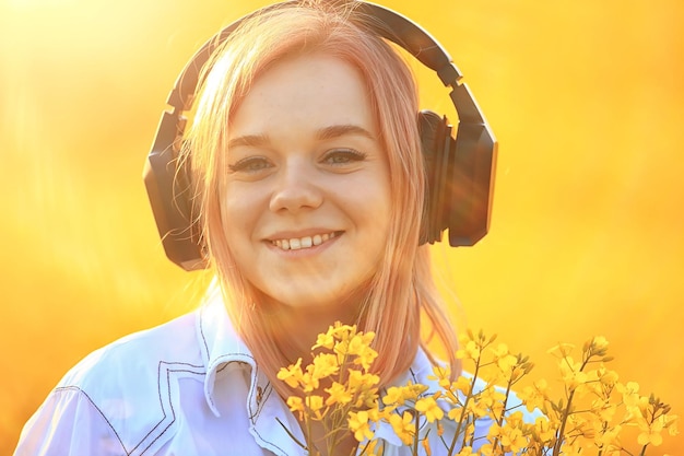 fones de ouvido de áudio verão música menina em um campo de flores, jovem primavera feminina