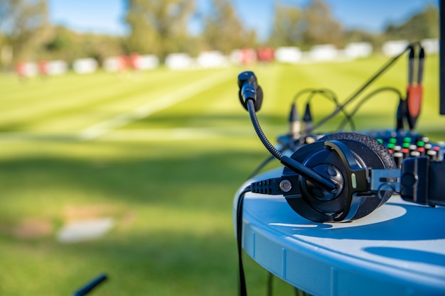 Fones de ouvido de comentarista na mesa ao lado do campo de futebol. transmissão para televisão e rádio