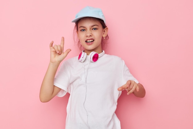 Fones de ouvido de menina em uma camiseta branca e um boné infância inalterado