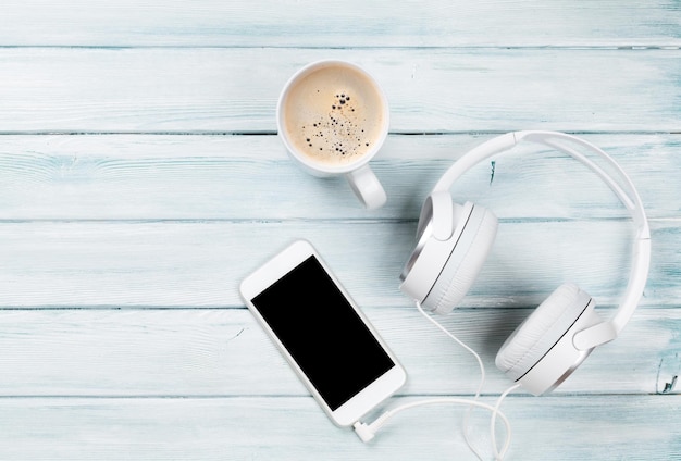 Fones de ouvido do smartphone e xícara de café
