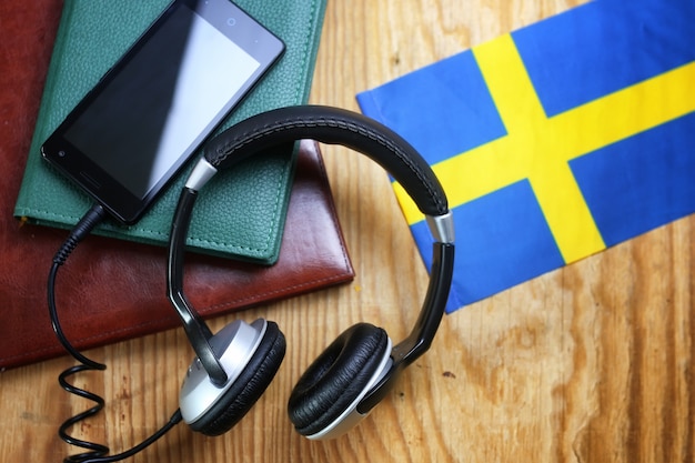 Fones de ouvido e bandeira em uma linguagem de curso de conceito de fundo de madeira