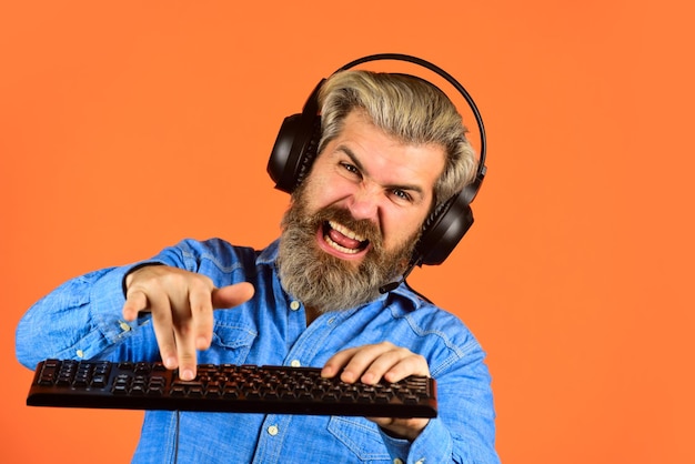 Fones de ouvido e teclado de gamer hipster barbudo Vício em jogos Desempenho superior Jogos online Lazer moderno Execute qualquer jogo moderno Configurações gráficas forçadas ao limite Jogue jogos de computador