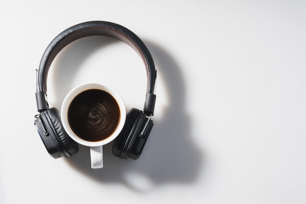 Fones de ouvido e xícara de café na mesa branca. Conceito de música. Vista do topo