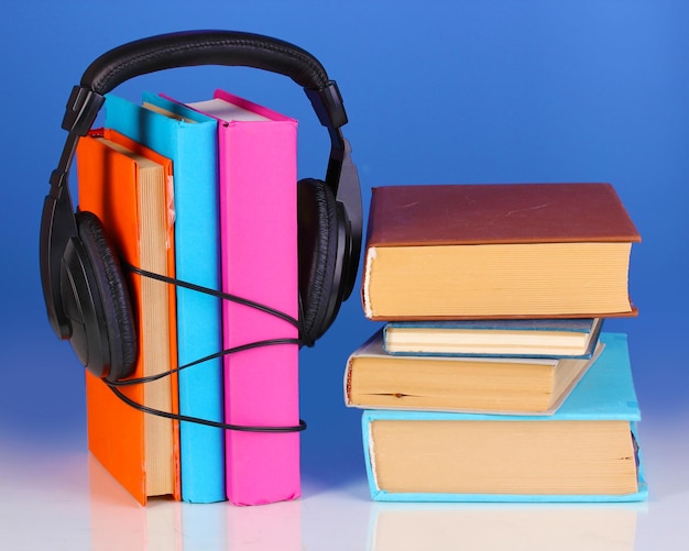 Foto fones de ouvido em livros em fundo azul