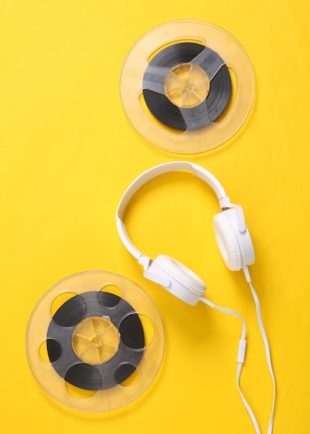 Fones de ouvido estéreo com carretel de áudio em fundo amarelo Retro dos anos 80 ainda vida Vista superior