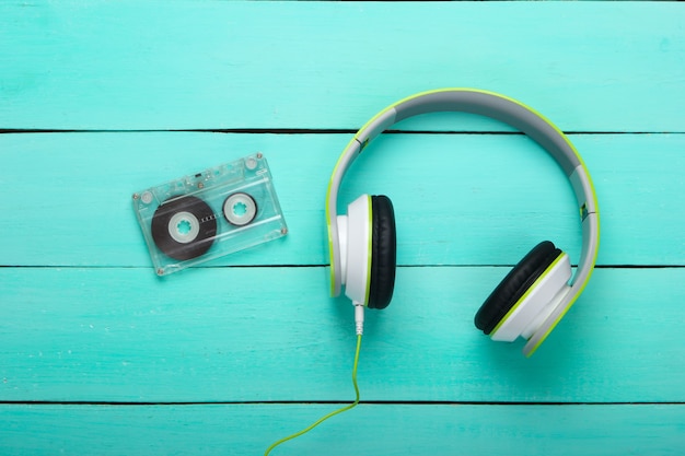 Fones de ouvido estéreo com fita cassete na mesa de madeira azul