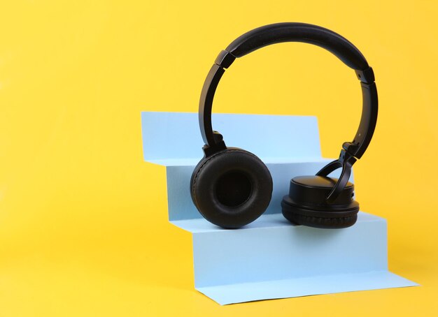 Fones de ouvido estéreo em escadas fundo amarelo minimalismo de arte conceitual