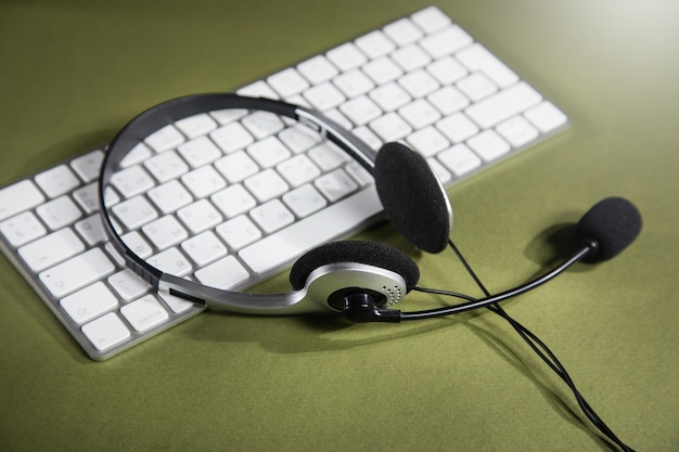 Fones de ouvido no teclado branco. conceito de serviço de suporte