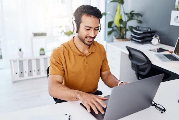 Fones de ouvido para laptop e homem de negócios ouvindo áudio de música e empresário asiático trabalhando na mesa para ouvir uma música enquanto digita para e-mail de pesquisa on-line ou mídia social com internet