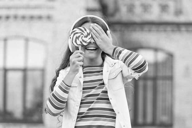 Fones de ouvido sem fio de menina comem o conceito de escolha cega de doces de pirulito