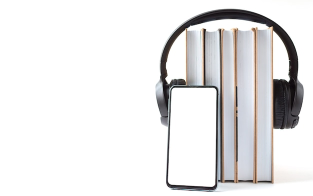 Fones de ouvido, telefone e livros em um fundo branco. Conceito de audiolivro.