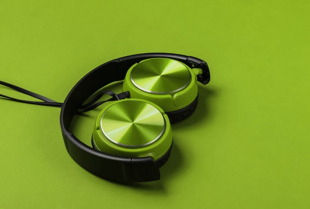 Fones de ouvido verdes com fio elegantes sobre fundo verde. conceito de amante da música.