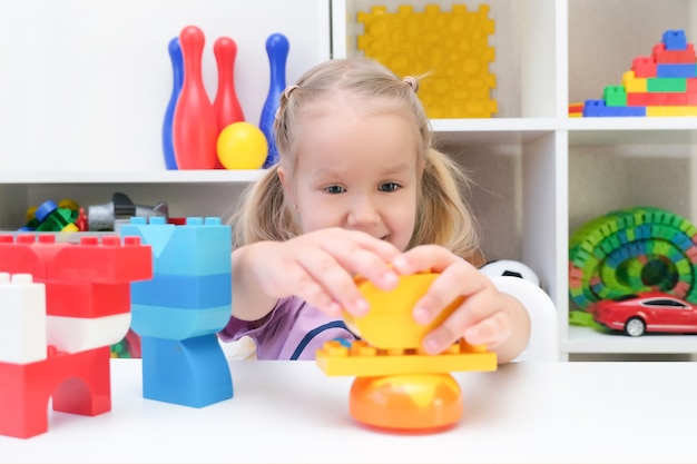 Fonoaudiologia, o desenvolvimento de habilidades motoras finas. Menina brincando de construtor, criança feliz