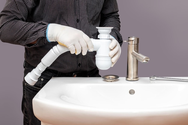 Foto un fontanero instala un sifón para un lavabo en un baño.