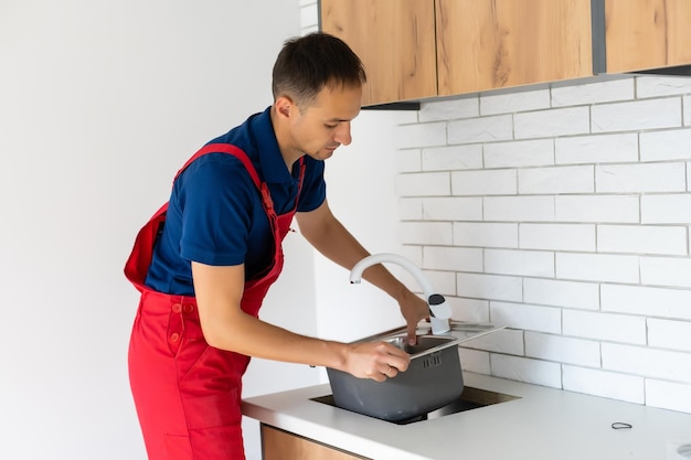 Fontanero poniendo un sellador de silicona para instalar un fregadero de cocina