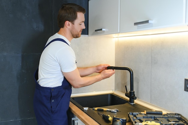 Fontanero profesional que fija el grifo de agua en la cocina