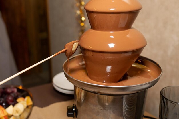 Foto fonte de chocolate para um aniversário ou casamento mergulhando uma banana em uma fonte de chocolate