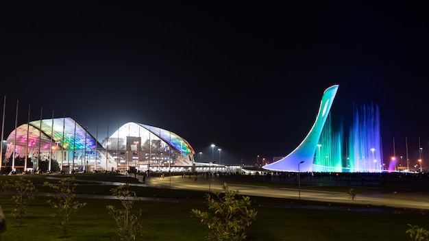 Fonte musical iluminada incrível e Estádio Olímpico "Fisht" à noite em Sochi, Rússia.