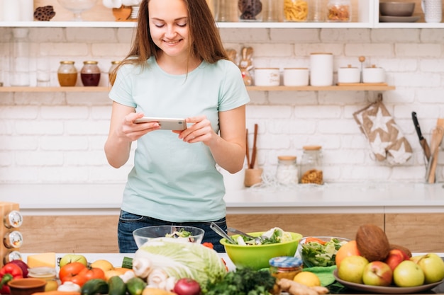 Food-Blogger. Gesunde Ernährung. Grünes Rezept. Frau mit Smartphone, das Foto von Frischgemüsesalat macht.