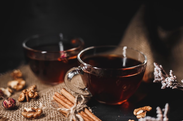 Food-Fotografie Zimt gebunden mit Bindfäden auf Sackleinen Eine Tasse heißen Tee aus Glas auf dunklem Hintergrund