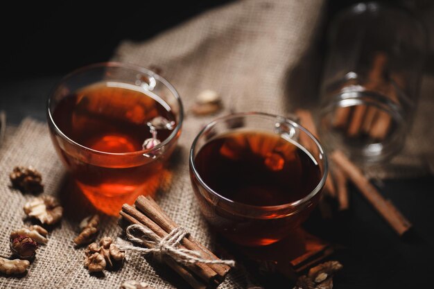 Food-Fotografie Zimt gebunden mit Bindfäden auf Sackleinen Eine Tasse heißen Tee aus Glas auf dunklem Hintergrund