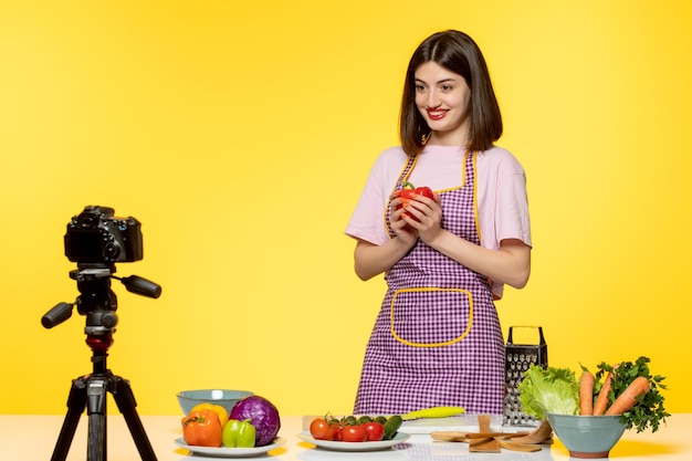 Foodblogger, süßer, reizender Koch in rosa Schürze, der ein Video für soziale Medien aufnimmt, freut sich auf einen Salat