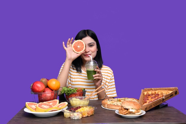 foodie chica sentada en la mesa de frutas sonriendo sosteniendo cítricos modelo paquistaní indio