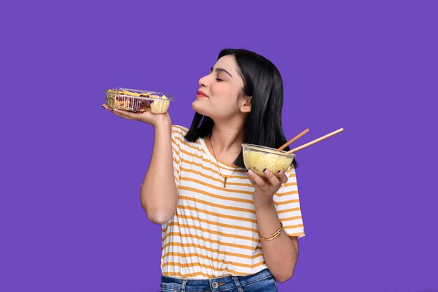 Foto foodie chica sosteniendo espaguetis y fideos posando sobre fondo morado indain modelo paquistaní