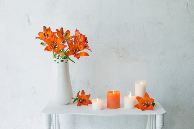 Foto forange flores y velas sobre fondo blanco.