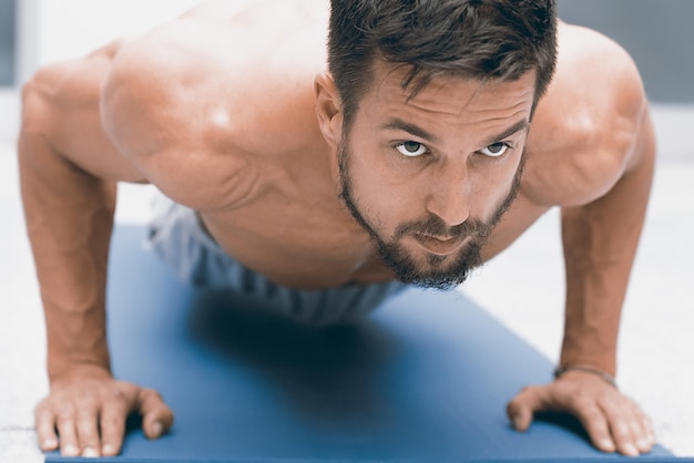 Foto força e motivação. jovem bonito fazendo flexão no ginásio