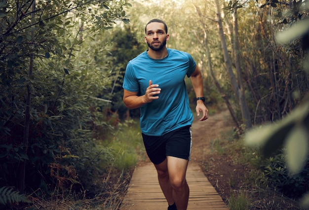 Forest fitness e corredor homem treinando para maratona no caminho de trilha no México com treino de cardio de concentração e objetivos de cara praticando velocidade de corrida para competição de atleta com foco