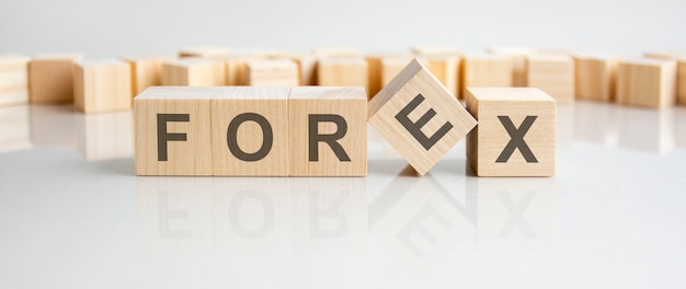 Forex - palavra de blocos de madeira com letras em um fundo cinza. reflexo da legenda na superfície espelhada da mesa. foco seletivo.