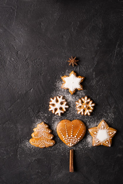 Form der Tanne des Lebkuchens auf schwarzem Hintergrund, Weihnachtskonzept, Kopierraum-Draufsicht, vertikal