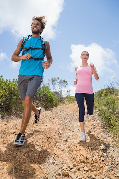 Forma atractiva pareja corriendo por el sendero de montaña