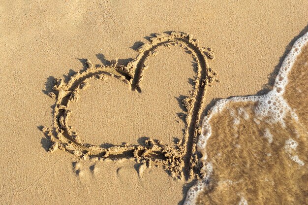 Foto forma de corazón en la arena de la playa del mar.